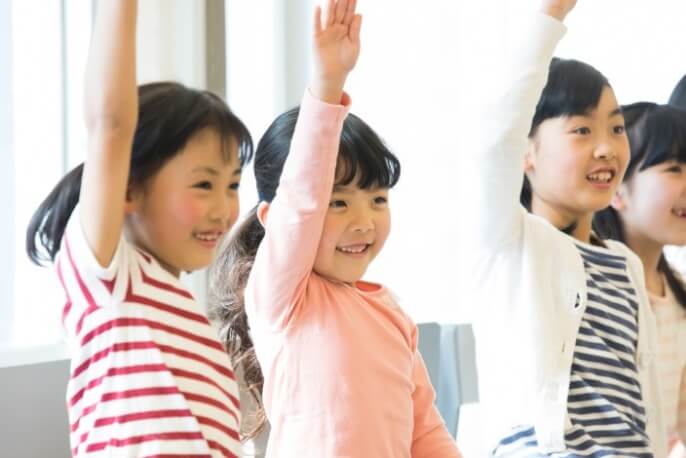 子供たちが授業で元気よく挙手をしている様子