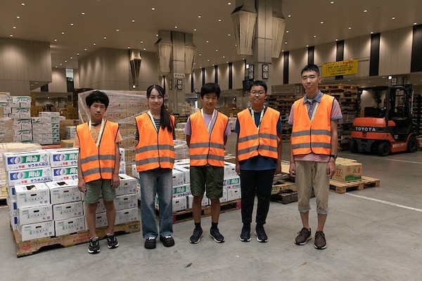 参加者の5人の中高生が作業着を着て並んでいる写真