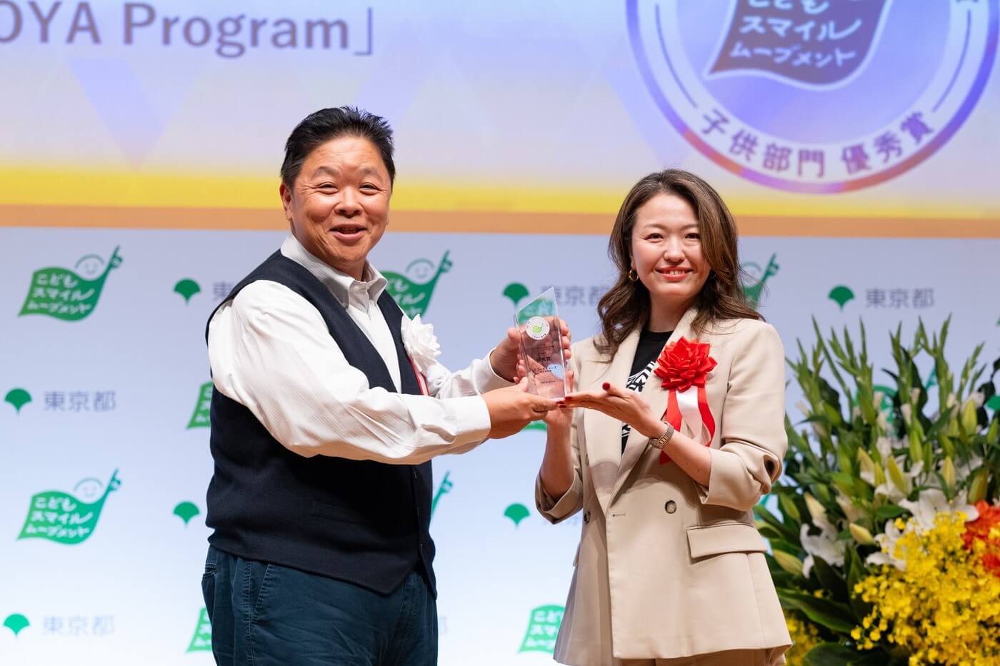 イコールチャンス株式会社の代表者がこどもスマイルムーブメントアンバサダーの伊集院光さんから優秀賞の盾を受け取っている様子