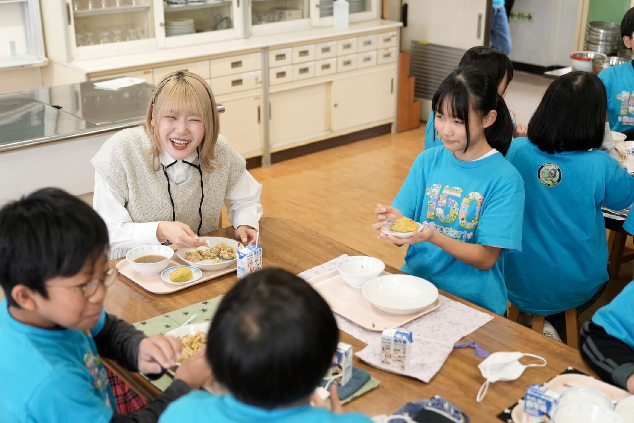 小学校の児童とハラミちゃんが一緒に給食を食べる様子