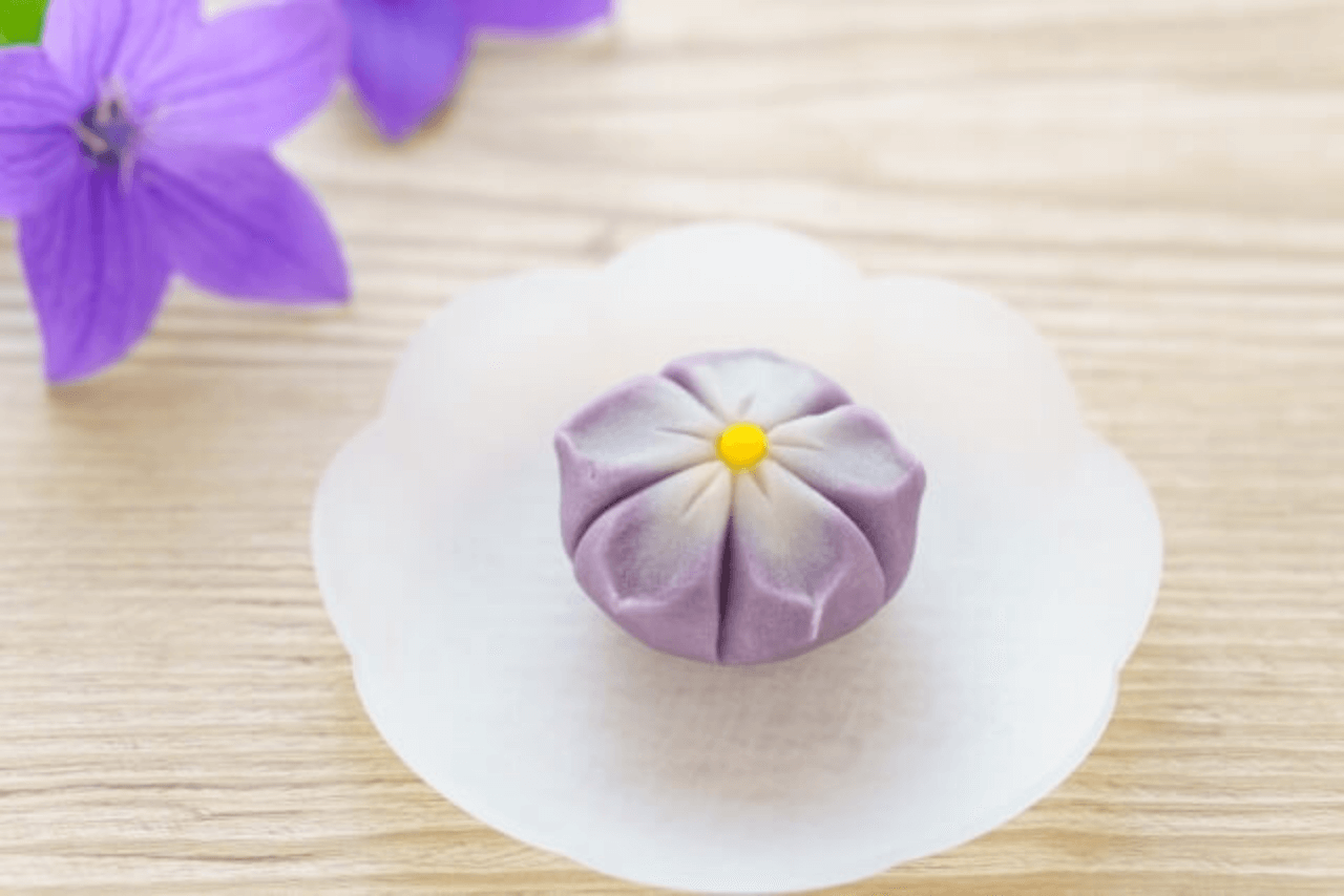 机の上に紫の花と一緒に置かれている紫の花をモチーフに作られた練り切り